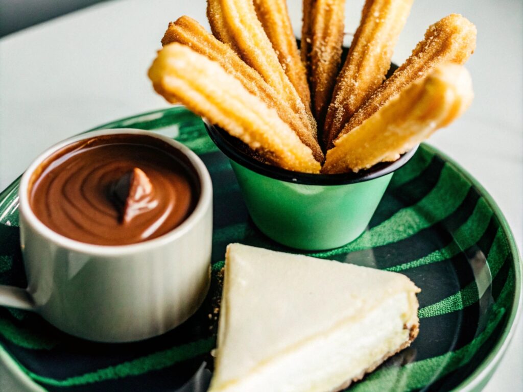 Churro cheesecake squares on a serving plate, dusted with cinnamon sugar and drizzled with caramel sauce