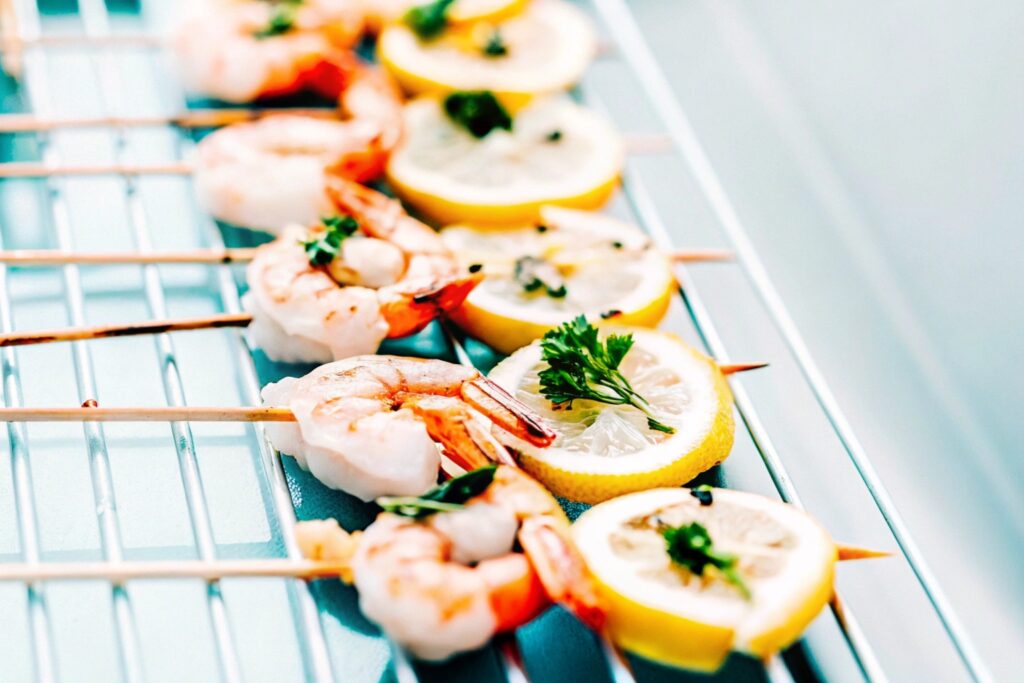 Grilled shrimp skewers sizzling on a barbecue grill, garnished with fresh parsley and lemon slices