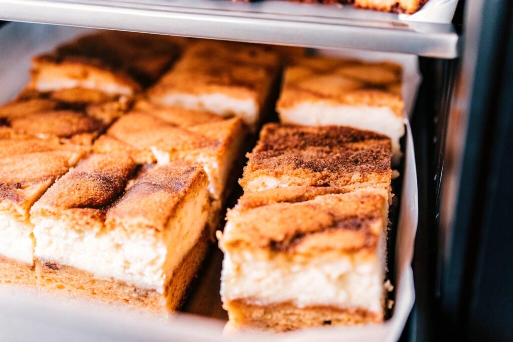 Churro cheesecake slices stored neatly in an airtight container, ready for refrigeration or serving.