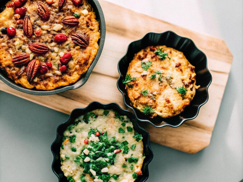 A table showcasing three styles of chicken dressing: one with cranberries and walnuts, another with a melted cheesy crust, and a third spiced with Cajun seasoning