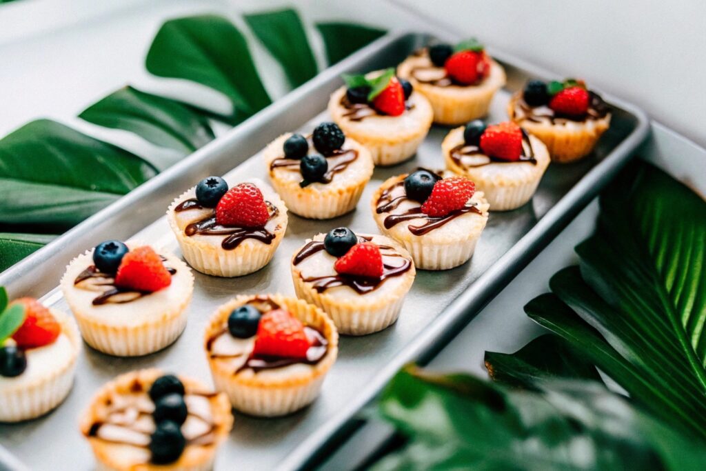 Mini churro cheesecake bites arranged on a platter, garnished with fresh berries and drizzled with chocolate sauce
