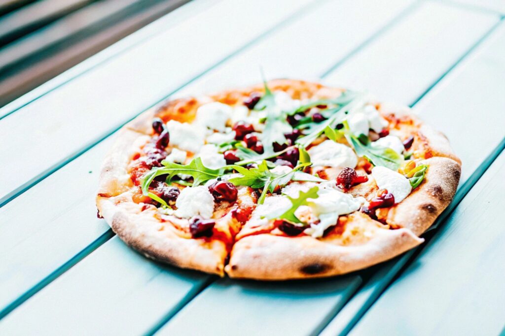 Rustic-style pizza topped with cranberry sauce, goat cheese, caramelized onions, and fresh arugula