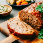 A beautifully sliced meatloaf on a rustic wooden cutting board, garnished with parsley, surrounded by side dishes like mashed potatoes and roasted veggies