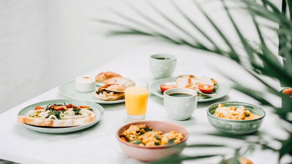 A cheerful table featuring chicken dishes like burritos, scrambles, and a breakfast bowl, with orange juice and coffee.