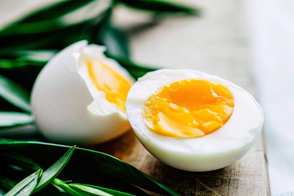 A cracked egg with a vibrant yellow yolk resting in the egg white on a rustic wooden surface