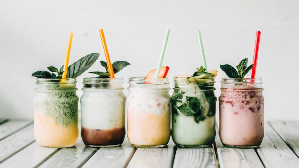 A colorful assortment of slushy drinks in mason jars, each with unique garnishes like fruit slices