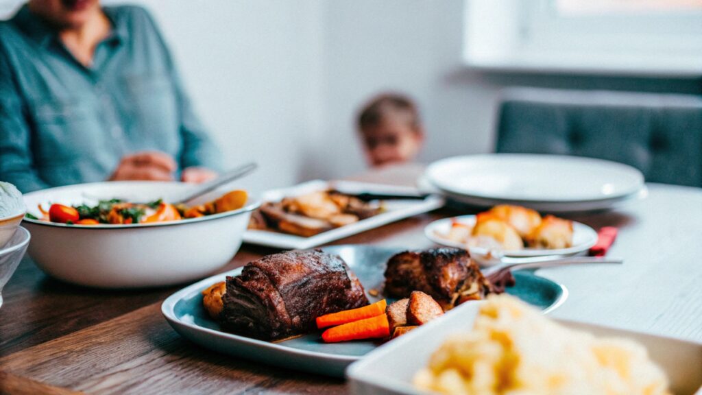 A family enjoying a meal featuring both boneless beef ribs and short ribs, served with mashed potatoes and roasted vegetables on a rustic table