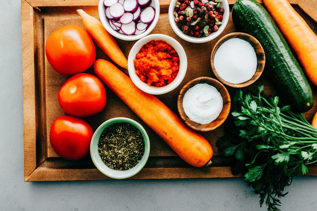 A flat-lay of all the ingredients neatly arranged on a wooden cutting board, including corn, bell pepper, jalapeño, cotija cheese, spices, and lime.