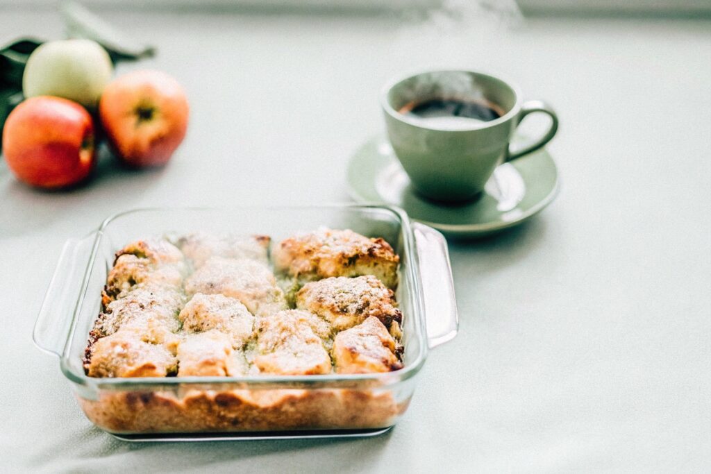 A golden-topped covered chicken casserole served with coffee and fresh fruit on a breakfast table