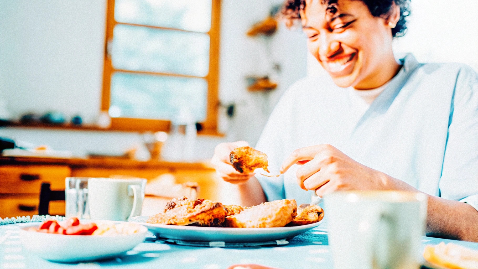 A happy, energized individual enjoying a chicken-based breakfast with a sunny kitchen background