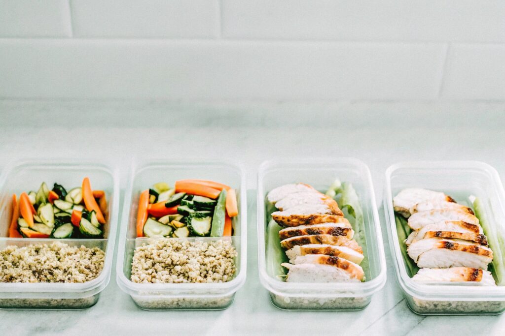 Meal prep containers filled with grilled chicken, quinoa, and an assortment of colorful vegetables