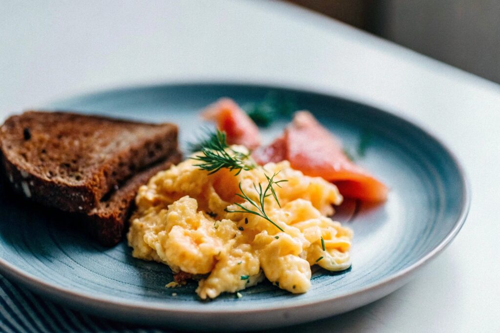 Grilled salmon fillet with sunny-side-up eggs and fresh parsley garnish on a breakfast plate.