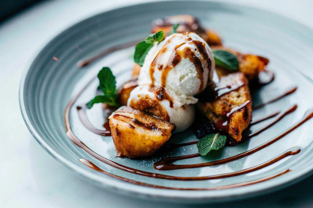 Fried banana slices served on a dessert plate with vanilla ice cream, caramel drizzle, and fresh mint garnish