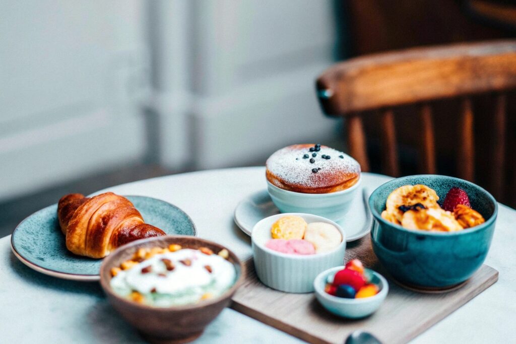 A rustic table featuring a variety of global breakfast dishes like croissants, soufflé pancakes, and smoothie bowls