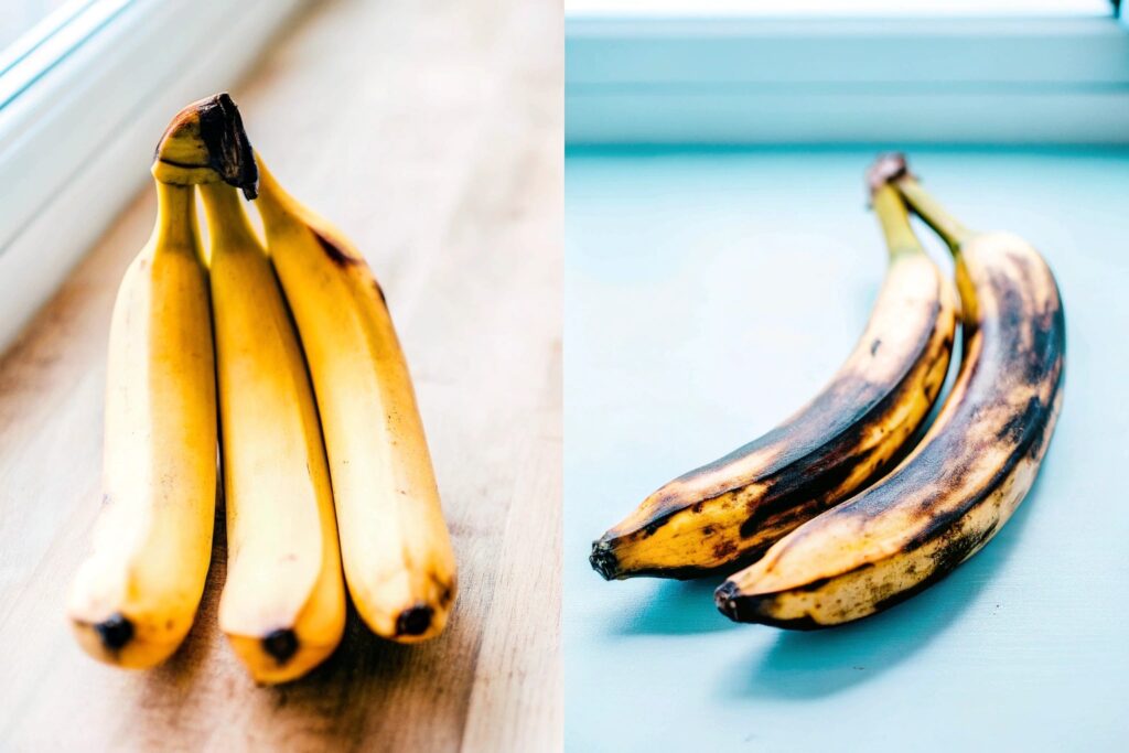 A comparison of ripe bananas and ripe plantains, showcasing their size and peel differences on a rustic wooden surface