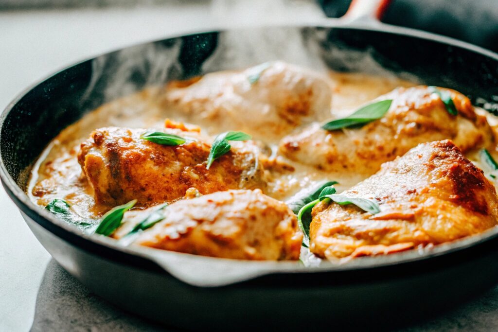 Golden-brown chicken pieces frying in a skillet with oil, creating a crispy coating.