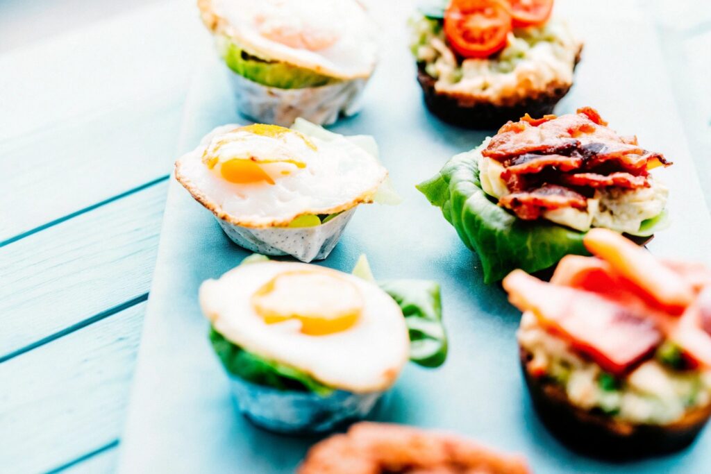 A spread of creative chicken breakfast dishes, including chicken muffins, lettuce wraps, and chicken avocado toast, displayed on a wooden table with fresh ingredients