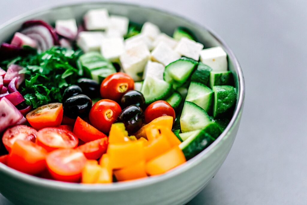 A vibrant bowl of Mediterranean quinoa salad with diced cucumbers, cherry tomatoes, olives, and crumbled feta cheese, garnished with fresh parsley