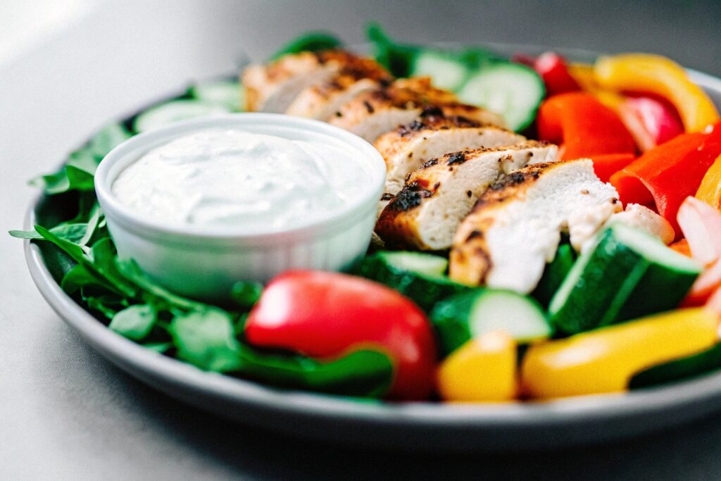 A vibrant Mediterranean-style breakfast platter featuring grilled chicken, fresh vegetables, and a side of Greek yogurt