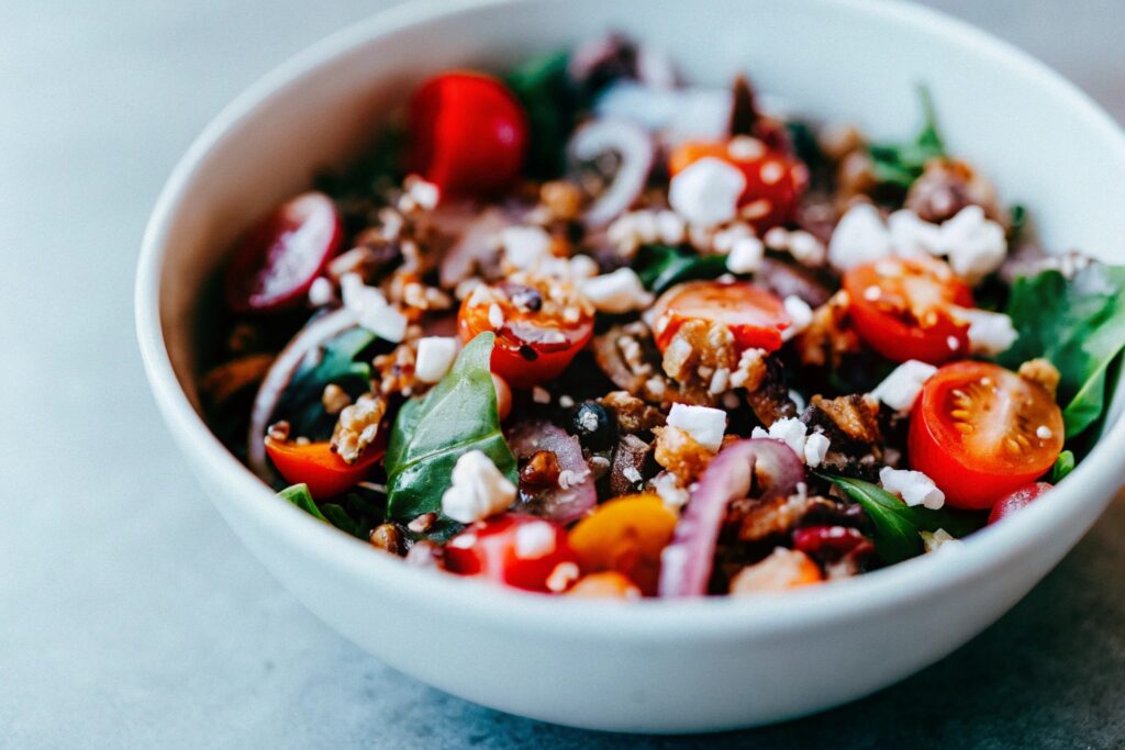 A vibrant salad with mixed greens, cherry tomatoes, red onions, pepitas, and a generous topping of cotija cheese