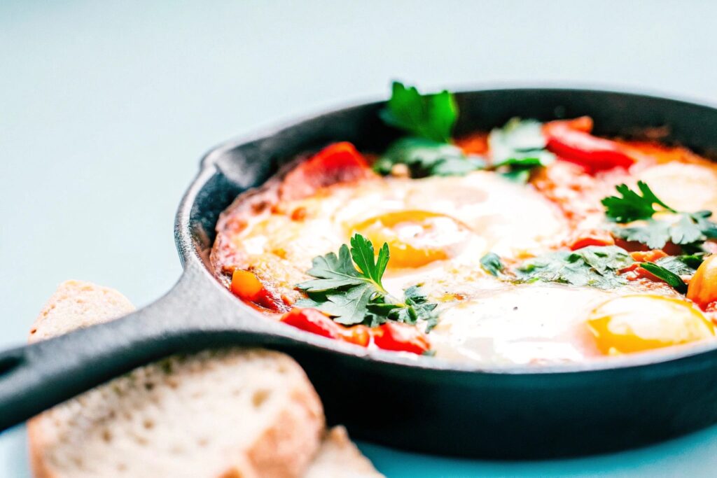 A vibrant shakshuka dish served in a cast-iron skillet, garnished with fresh parsley and accompanied by slices of crusty bread