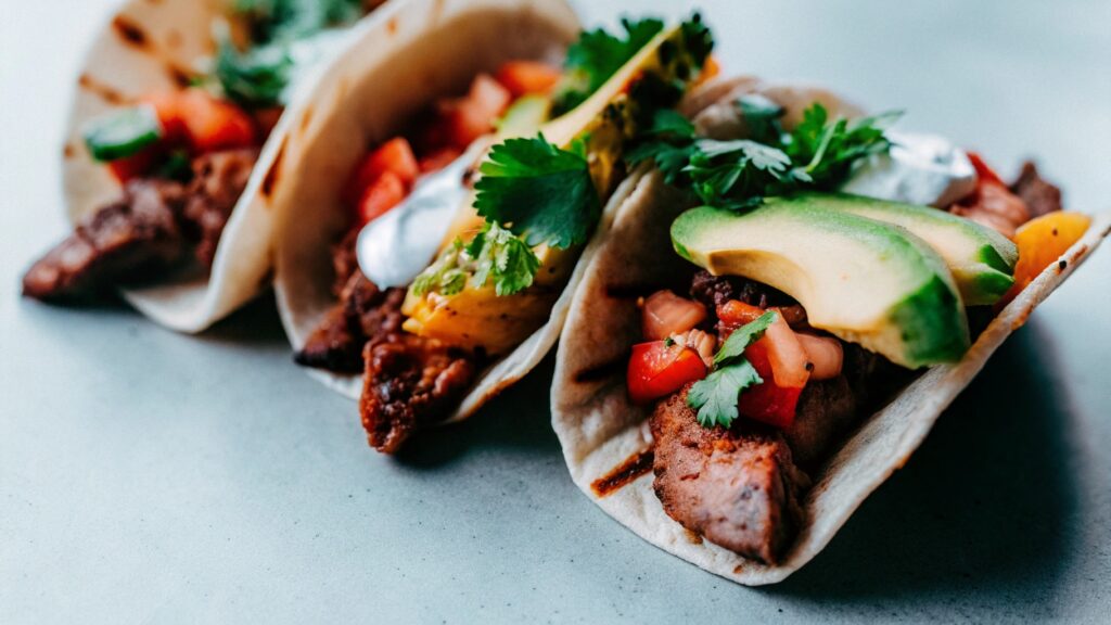 Chipotle-style steak served in tacos, burrito bowls, and with pineapple salsa on a colorful spread