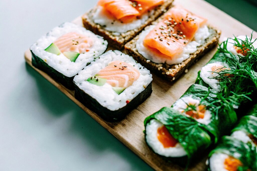 An assortment of global breakfast dishes featuring salmon, such as sushi, smoked salmon with rye bread, and grilled salmon with rice