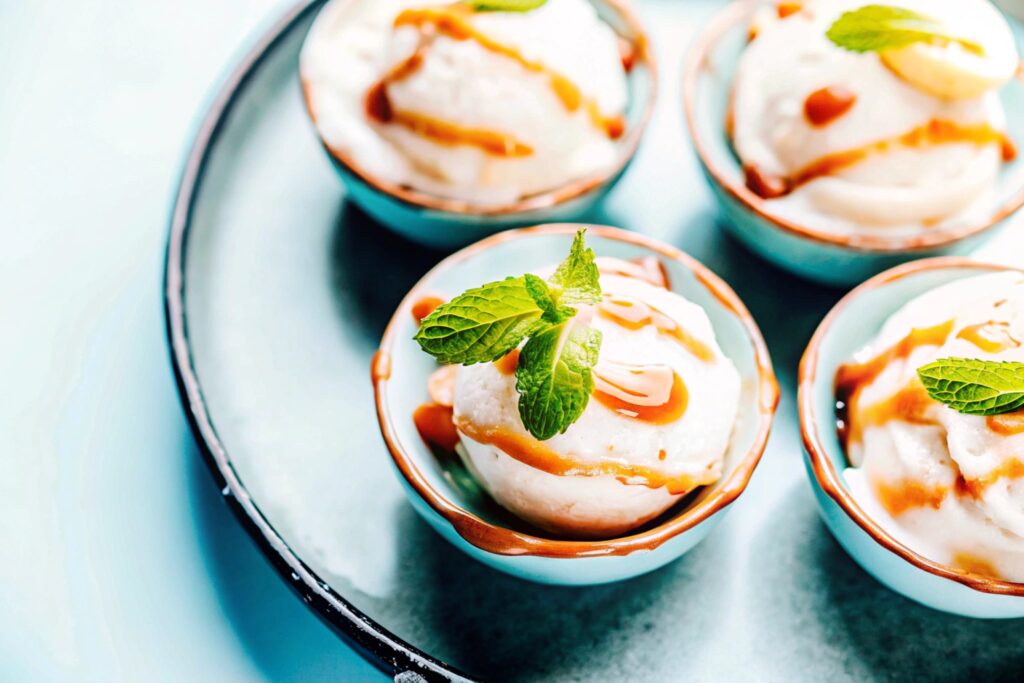 Frozen banana pudding served in small dessert bowls, topped with a caramel drizzle and a fresh mint leaf garnish