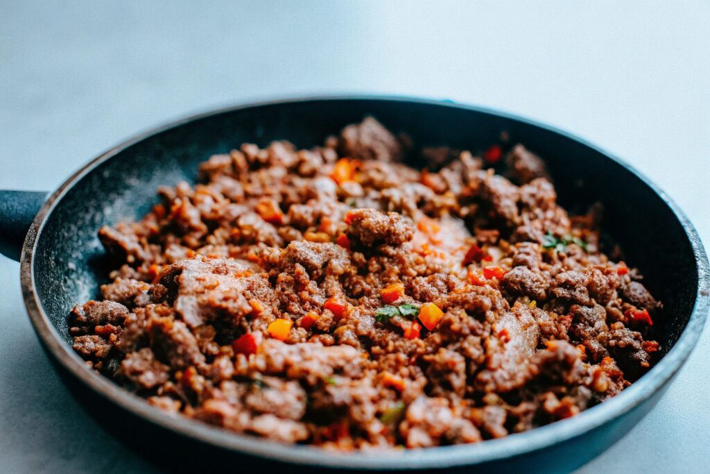 Ground beef sizzling in a skillet and vibrant spices sprinkled over it