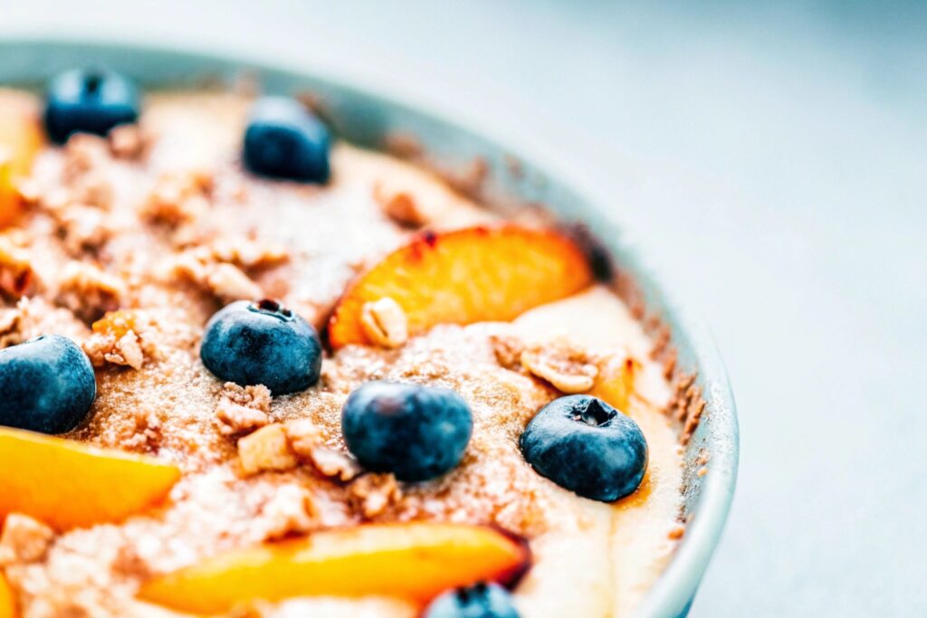 A rustic cast iron skillet filled with warm peach cobbler, placed on a wooden table with a checkered cloth