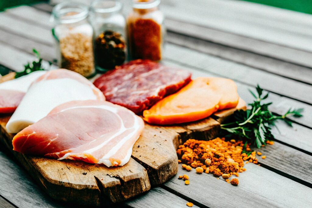 A variety of wood chips, spices, and cuts of meat laid out on a rustic wooden table, ready for preparation