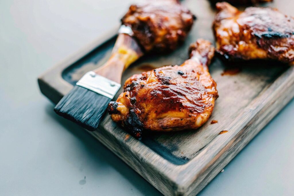 Golden smoked chicken thighs glazed with honey mustard, arranged on a cutting board with a basting brush and sauce nearby