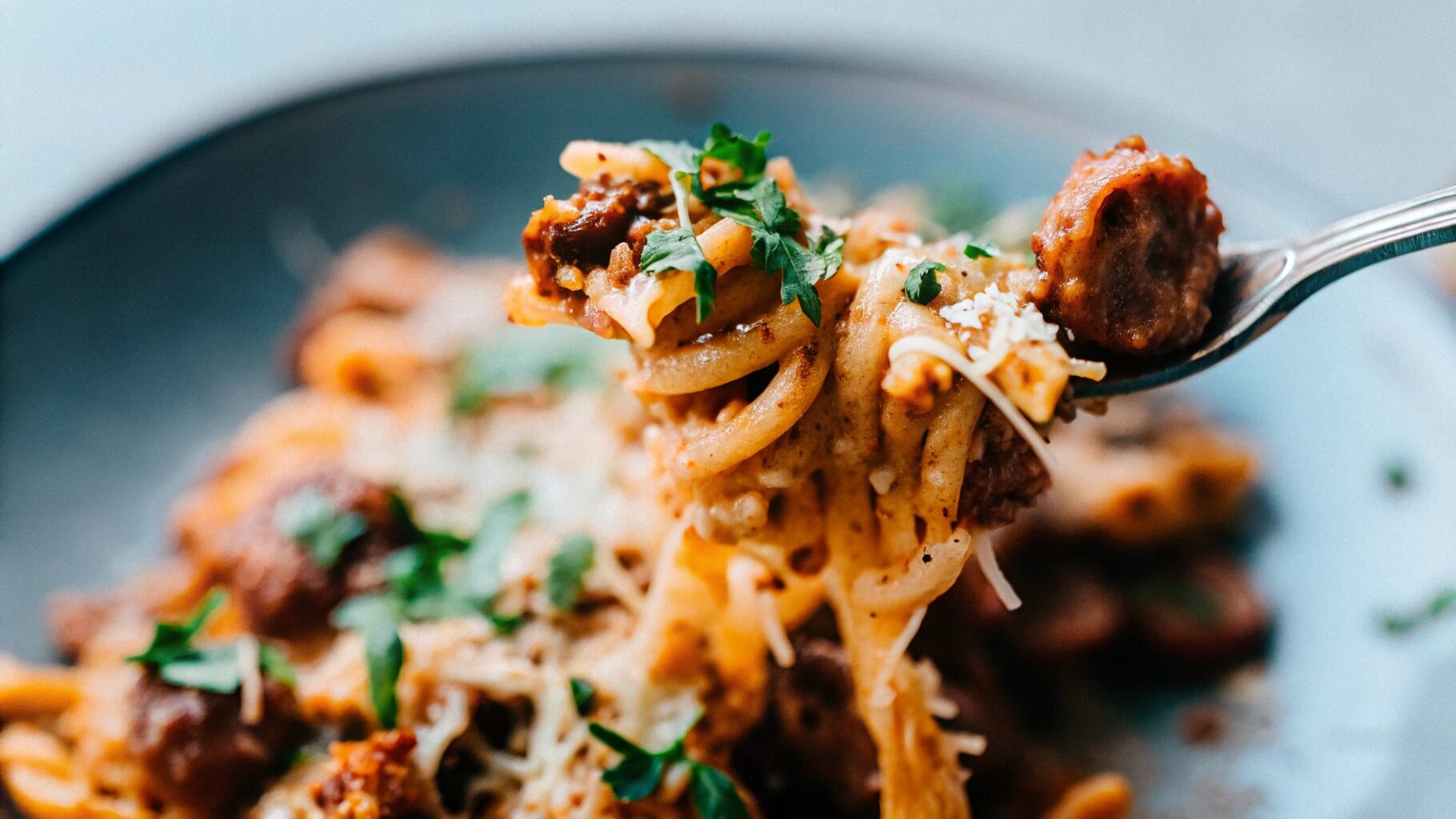 A beautifully plated serving of cheesy kielbasa pasta bake with a fork twirling a bite of cheesy pasta, ready to be enjoyed